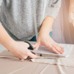 Young seamstress makes clothes cutting fabric